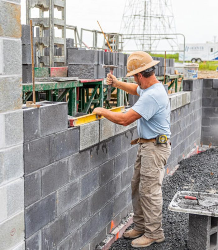 Man laying a block wall on a new construction site