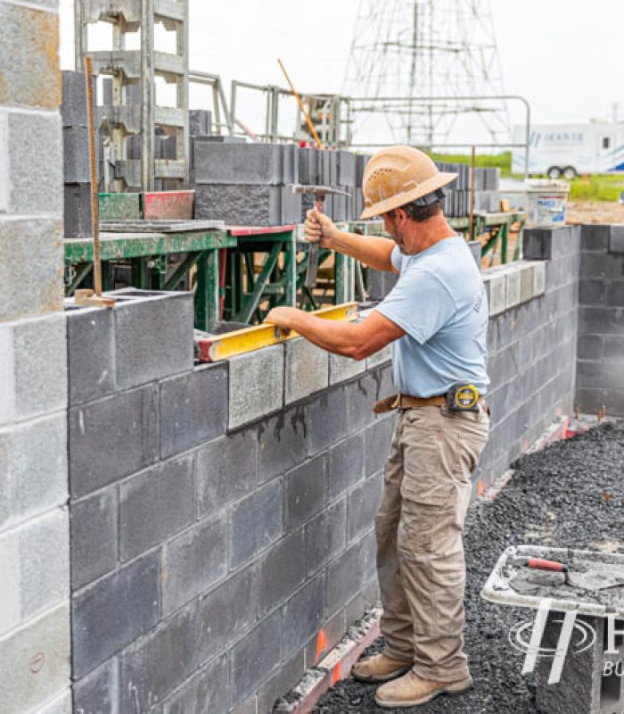 Man laying a block wall on a new construction site