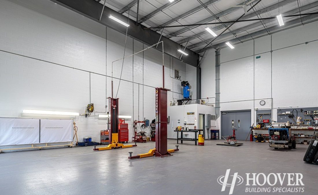 view of newly constructed interior warehouse with cement flooring and equipment